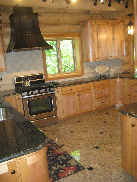 kitchen with custom exhaust hood, decorative backsplash, stainless steel range with gas cooktop, and light brown cabinetry