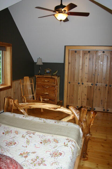 bedroom featuring a ceiling fan, lofted ceiling, and wood finished floors