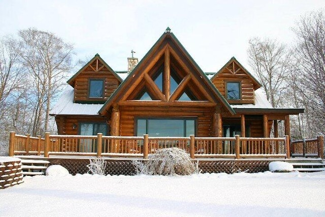 view of front of property with log siding, covered porch, and a chimney