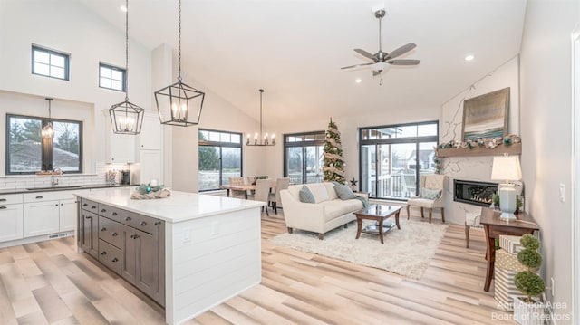 kitchen featuring sink, light stone counters, hanging light fixtures, white cabinets, and backsplash