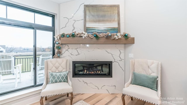 sitting room with a high end fireplace, plenty of natural light, and wood-type flooring