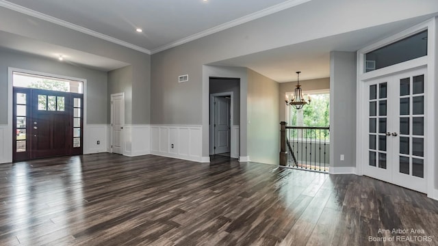 foyer entrance with crown molding, dark hardwood / wood-style floors, a chandelier, and french doors