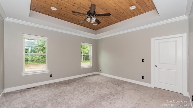 empty room featuring wood ceiling, light colored carpet, and a tray ceiling