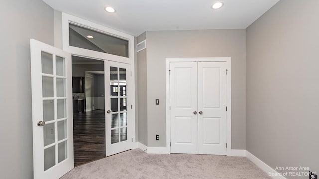 unfurnished bedroom with french doors, light carpet, and a closet