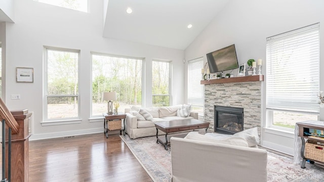 living room with hardwood / wood-style floors, a stone fireplace, and high vaulted ceiling