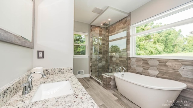 bathroom with independent shower and bath, vanity, hardwood / wood-style floors, and tile walls