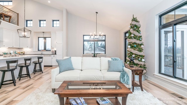 living room with a notable chandelier, sink, light hardwood / wood-style floors, and a wealth of natural light