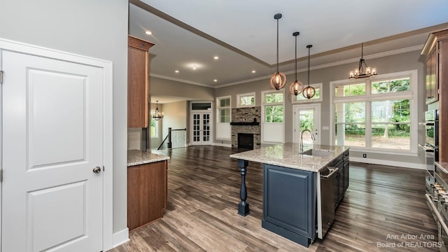 kitchen featuring a breakfast bar, sink, decorative light fixtures, an island with sink, and light stone countertops