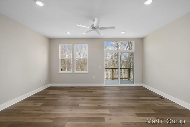 spare room with ceiling fan, dark wood-type flooring, and a wealth of natural light