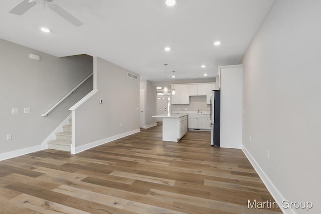 unfurnished living room featuring hardwood / wood-style floors, ceiling fan, and sink