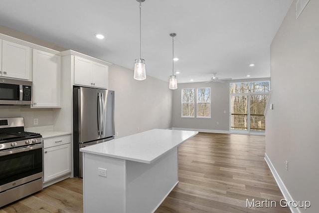 kitchen featuring stainless steel appliances, white cabinets, ceiling fan, and light hardwood / wood-style flooring