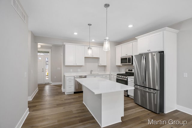 kitchen with decorative light fixtures, white cabinets, a kitchen island, dark hardwood / wood-style floors, and stainless steel appliances