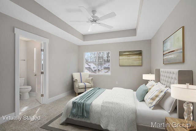 carpeted bedroom with ensuite bathroom, a raised ceiling, and ceiling fan