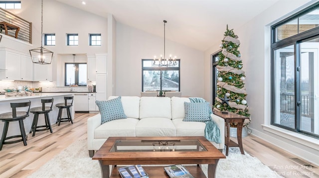 living room featuring an inviting chandelier, plenty of natural light, and light wood-type flooring