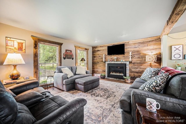 living room with a fireplace, wooden walls, and beamed ceiling