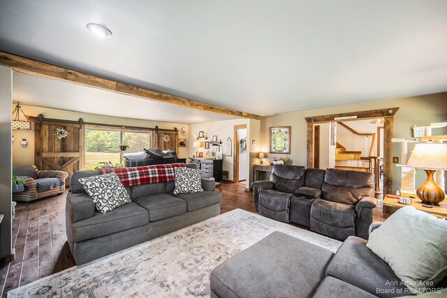 living room with dark wood-type flooring, beam ceiling, and a barn door