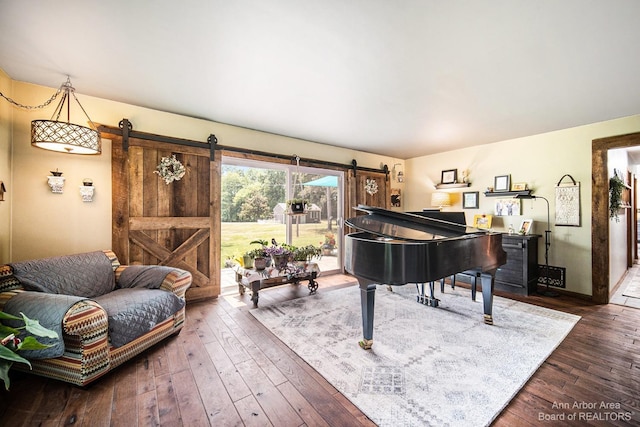 sitting room with a barn door and dark hardwood / wood-style flooring