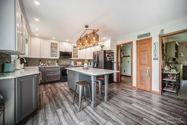 kitchen featuring white cabinets, a center island, stainless steel appliances, hanging light fixtures, and gray cabinetry