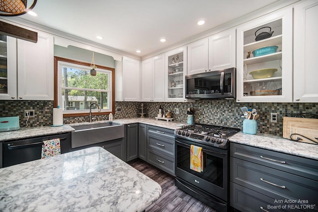 kitchen with appliances with stainless steel finishes, white cabinets, light stone counters, and sink