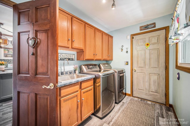 washroom with washer and dryer, sink, light hardwood / wood-style flooring, and cabinets