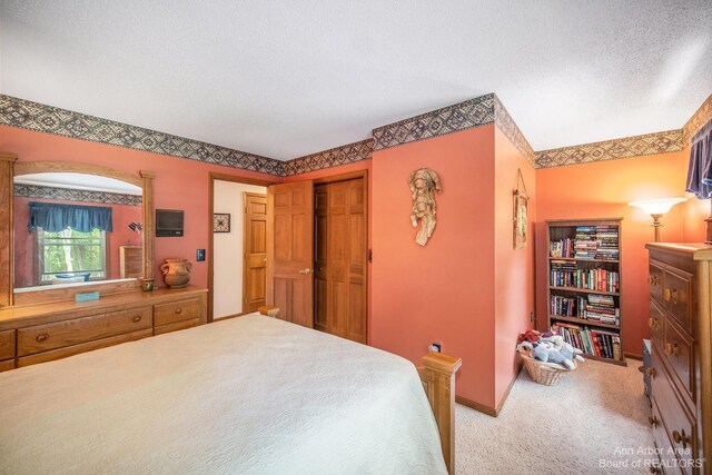 carpeted bedroom featuring a textured ceiling and a closet