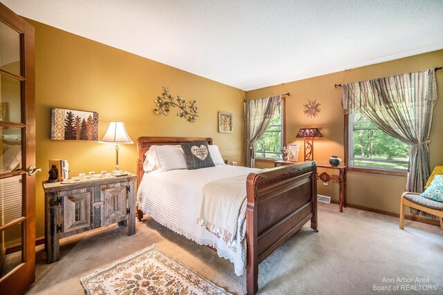 bedroom with multiple windows, a textured ceiling, and carpet flooring