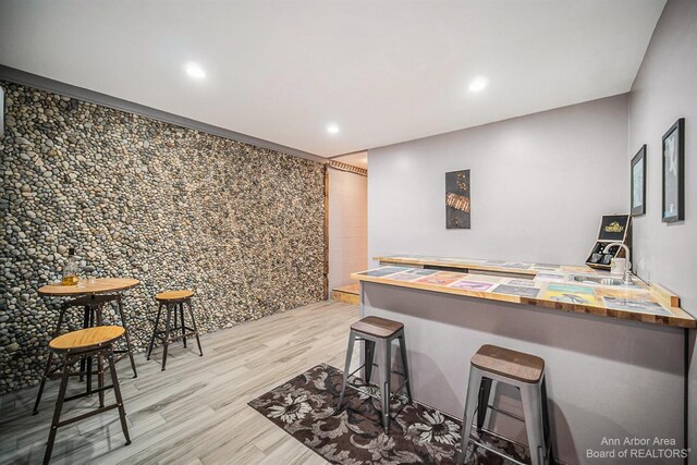 bar with light wood-type flooring, wooden counters, and sink