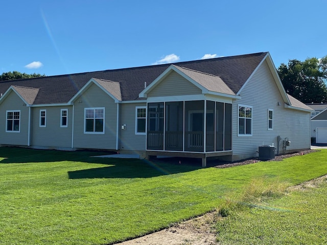 back of property with a sunroom, a yard, and central AC