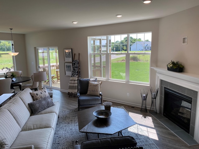 living room with a tiled fireplace and dark hardwood / wood-style flooring