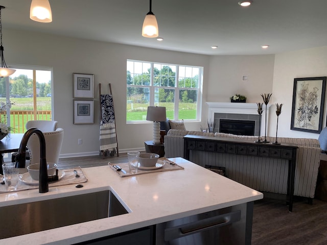 kitchen with a tiled fireplace, sink, decorative light fixtures, and dark wood-type flooring