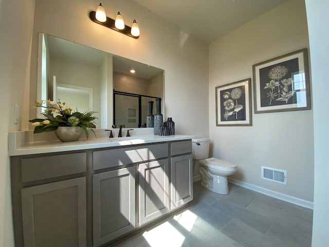 bathroom with tile patterned floors, vanity, toilet, and a shower with shower door