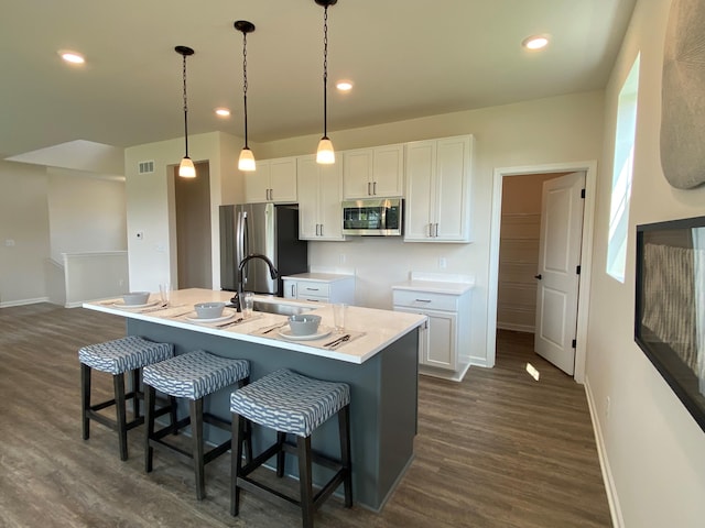 kitchen featuring stainless steel appliances, a kitchen island with sink, sink, and white cabinets