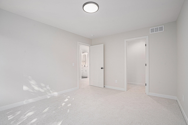 unfurnished bedroom featuring a walk in closet and light colored carpet