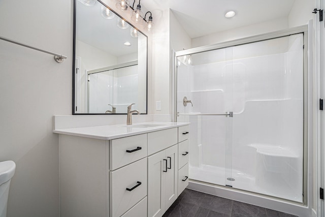 bathroom featuring vanity, toilet, and a shower with shower door