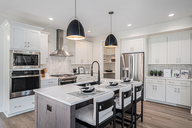 kitchen with stainless steel appliances, white cabinetry, and wall chimney exhaust hood