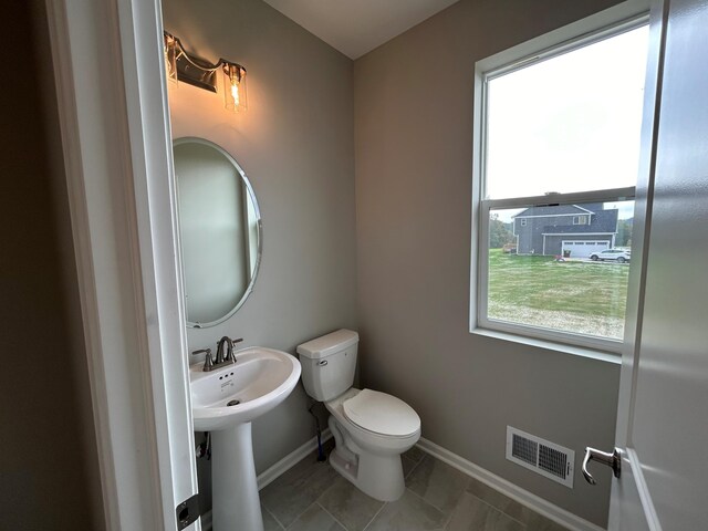 bathroom with tile patterned flooring, toilet, and a wealth of natural light