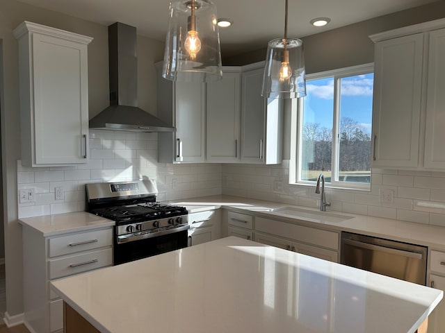 kitchen featuring sink, wall chimney exhaust hood, appliances with stainless steel finishes, tasteful backsplash, and white cabinetry