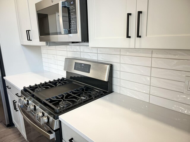 kitchen featuring decorative backsplash, white cabinetry, hardwood / wood-style flooring, and appliances with stainless steel finishes