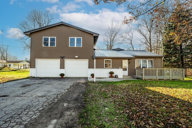 view of front of property with aphalt driveway, a front lawn, metal roof, and an attached garage