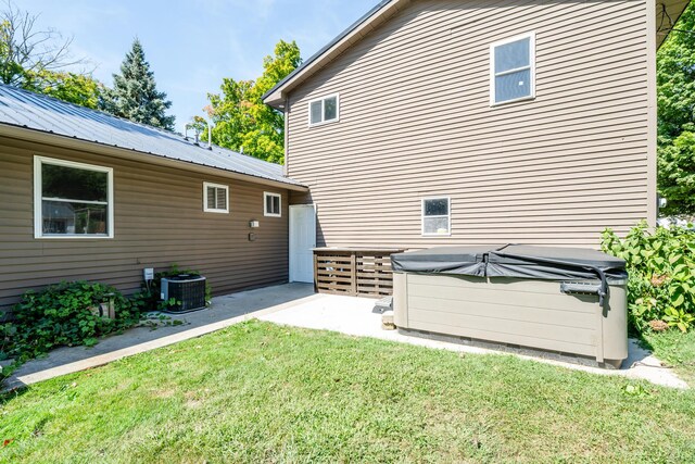 exterior space featuring a lawn, a hot tub, and central AC unit