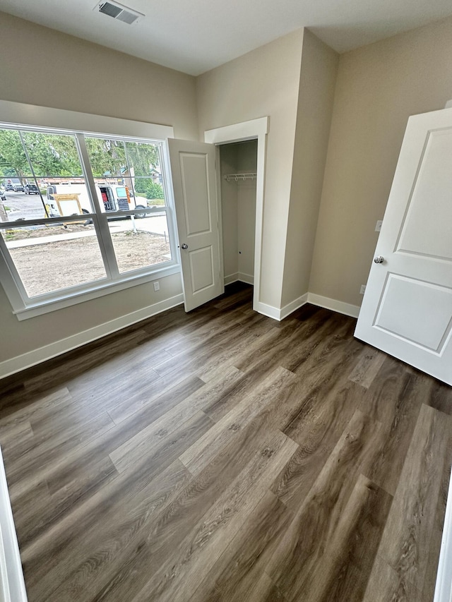 unfurnished bedroom with dark wood-type flooring and a closet