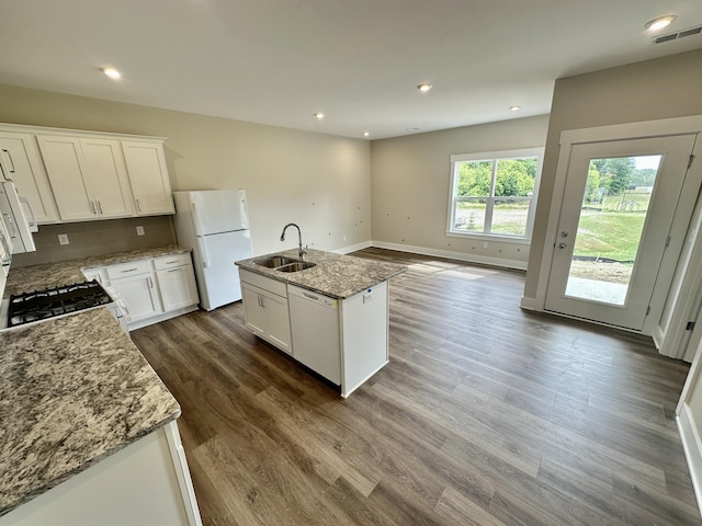 kitchen featuring white appliances, light stone countertops, an island with sink, and white cabinets