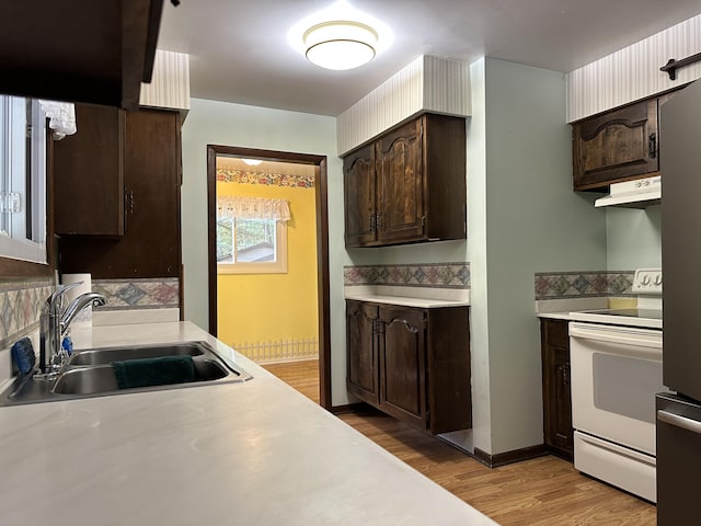 kitchen with white electric range, sink, dark brown cabinets, and light hardwood / wood-style flooring