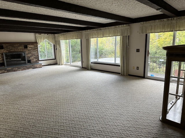 unfurnished living room featuring a fireplace, beam ceiling, and carpet floors