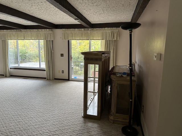 doorway to outside with beam ceiling, a textured ceiling, and carpet