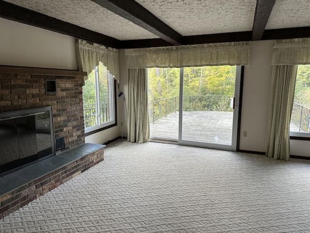 unfurnished living room featuring beamed ceiling, a fireplace, and carpet floors