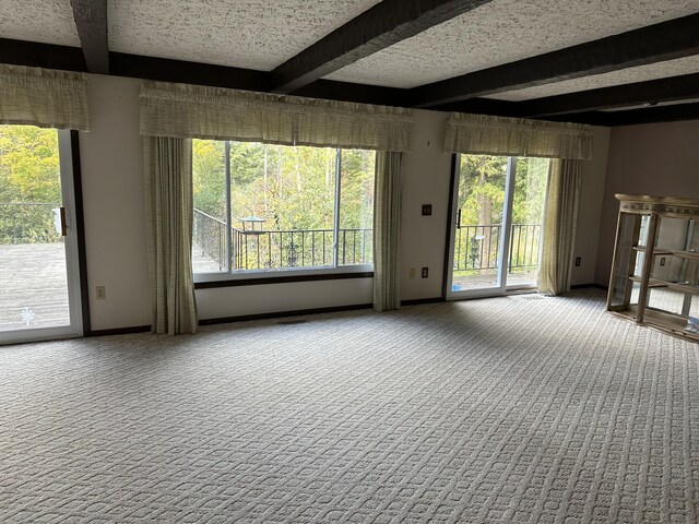 carpeted spare room featuring a textured ceiling and beamed ceiling