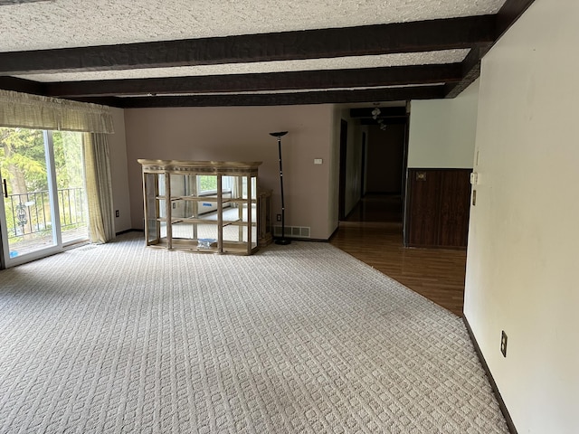 carpeted spare room featuring beam ceiling