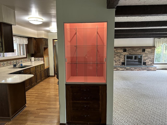 kitchen with wine cooler, sink, beam ceiling, dark brown cabinets, and a fireplace