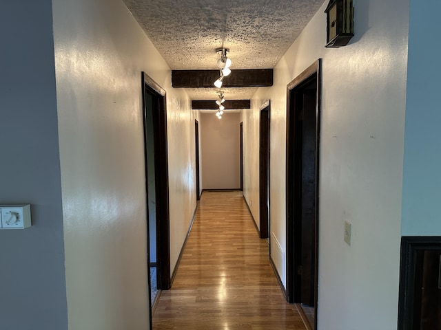 hallway featuring beam ceiling and hardwood / wood-style flooring